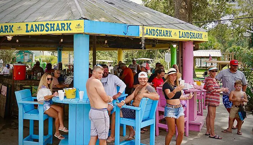 People are enjoying themselves at a colorful outdoor bar with the LANDSHARK branding