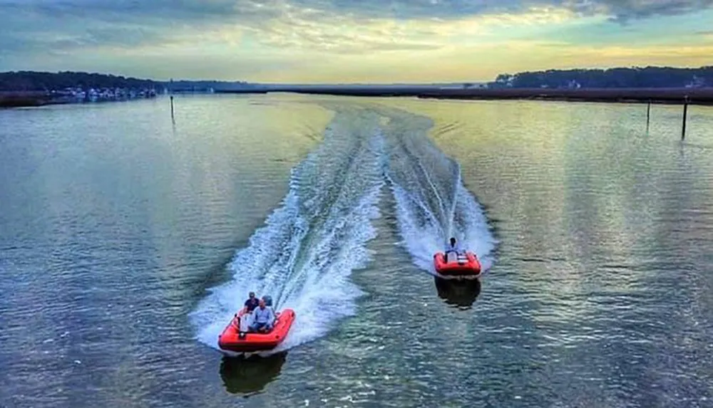 Two boats create symmetrical wake patterns on a calm waterway at dusk