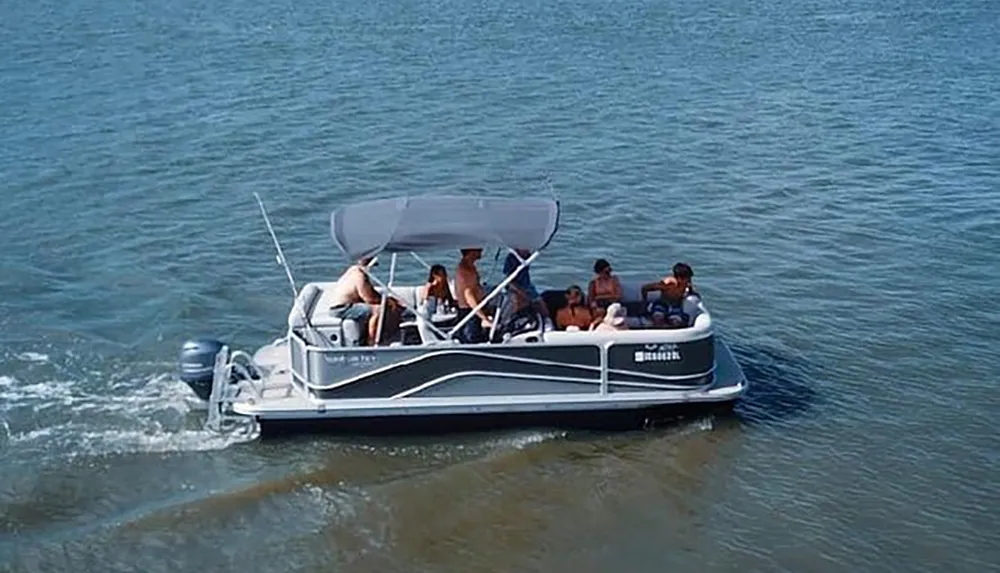 A group of people is enjoying a sunny day out on a pontoon boat on calm water