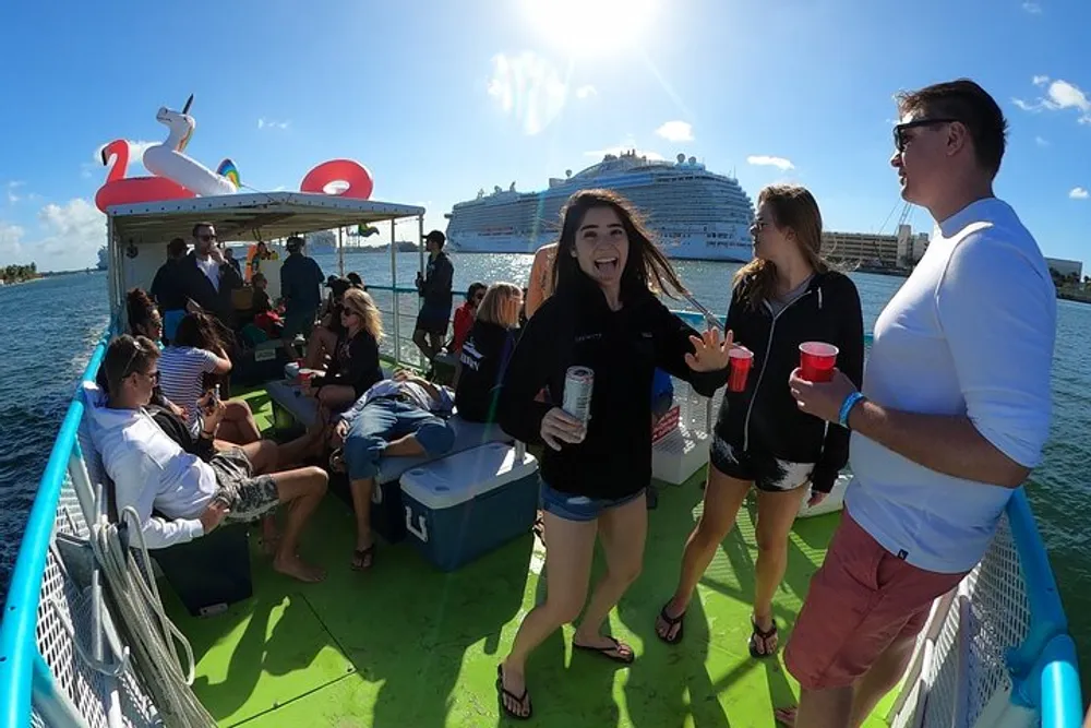 A group of people enjoy a sunny day on a boat with a large cruise ship in the background