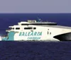 A white and blue high-speed ferry labeled BALEARIA CARIBBEAN is cruising on the open sea
