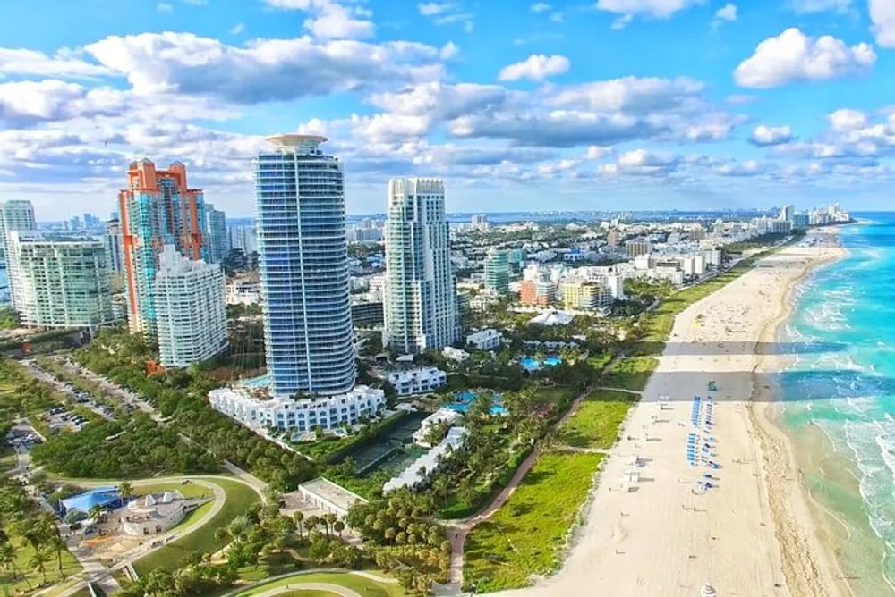 An aerial view of a sunlit Miami Beach coastline showcasing high-rise buildings pristine sands and a vibrant blue ocean