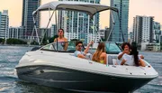 A group of people is enjoying a boat ride on the water with a city skyline in the background during dusk.