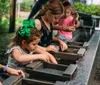 Children are engrossed in gemstone mining at a water-filled sluice with wooden trays