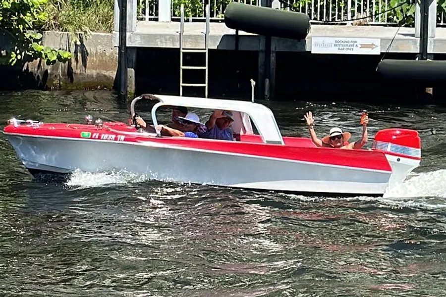 Passengers are enjoying a ride in a red and white speedboat cruising through water.