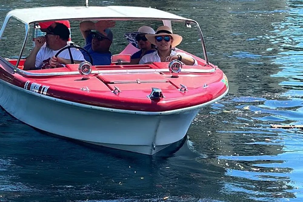 A group of people is enjoying a sunny boat ride on a vibrant red and white boat