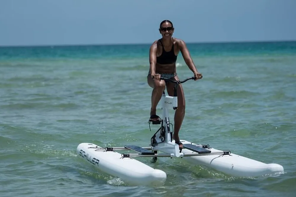 A person is riding a water bike on a calm sea smiling at the camera