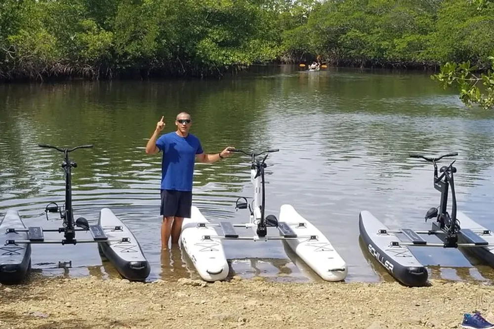 A person is posing with a peace sign in front of three water bikes near the edge of a water body likely introducing or showcasing them