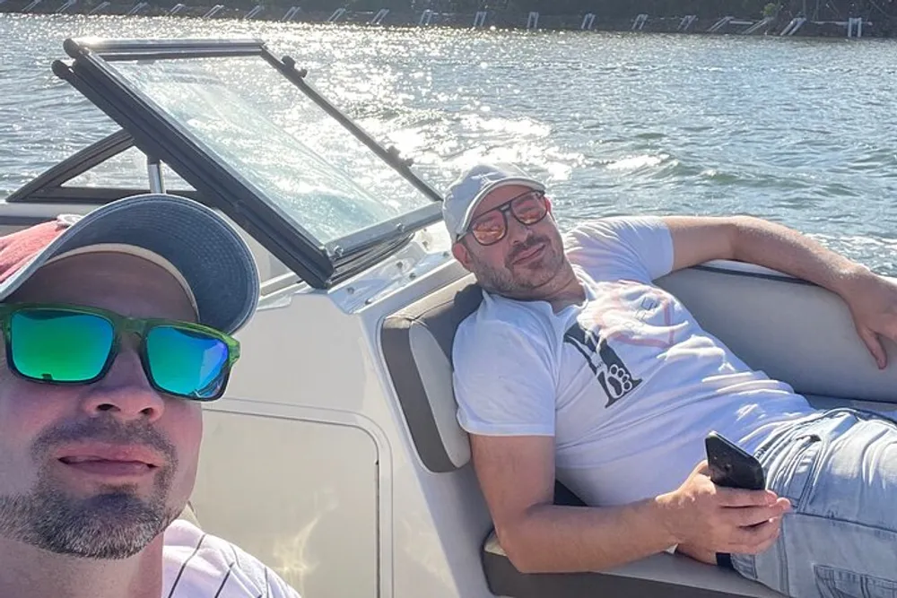 Two men are enjoying themselves on a sunny day aboard a boat with one of them taking a selfie