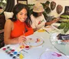 Two individuals are engaged in painting on oval-shaped canvases at a table adorned with painting supplies exhibiting a creative and enjoyable activity