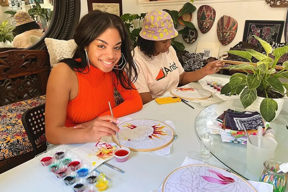 Two people are engaged in a creative painting activity with bright smiles and an array of art supplies on a table decorated with various designs