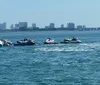 A person is riding a jet ski on a clear day with a cityscape in the background