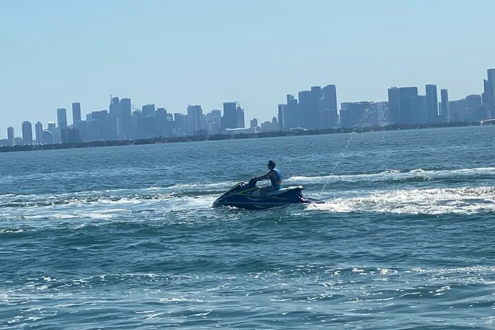 A person is riding a jet ski on the water with a city skyline in the background