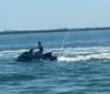 A person is riding a jet ski on a clear day with a cityscape in the background