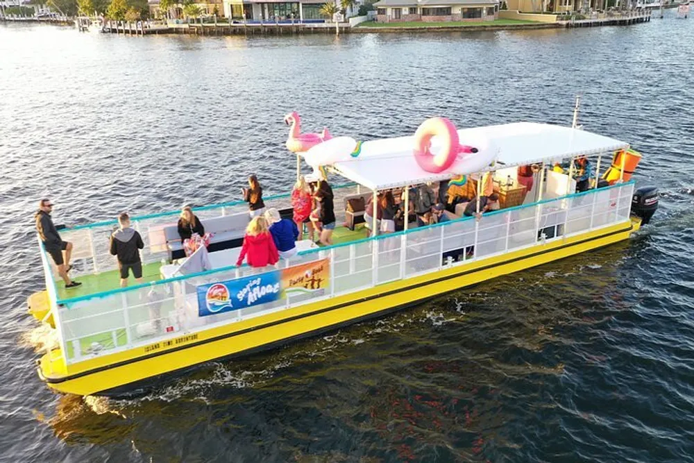 A group of people is enjoying a boat cruise on a sunny day with inflatable flamingos on board