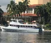 A white yacht named WHITE STAR is cruising on a river with a backdrop of palm trees and a building