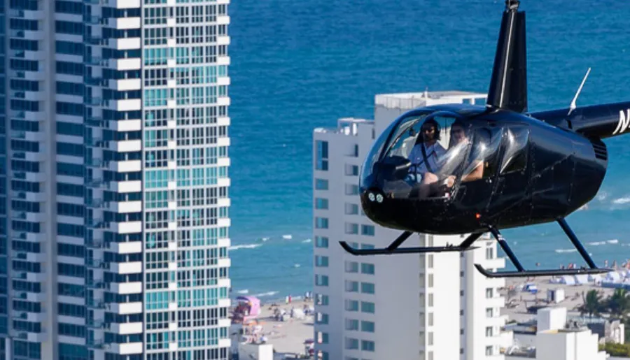 A helicopter with passengers is flying close to high-rise buildings near a beachfront.