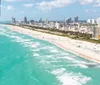 A helicopter with passengers is flying close to high-rise buildings near a beachfront