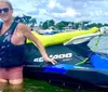 Two people are enjoying a jet ski ride on a sunny day with waterfront houses in the background