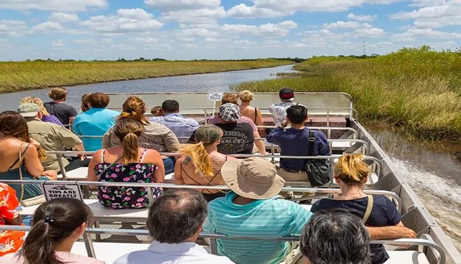 Tourists on an airboat tour enjoy the scenery of a grassy wetland.