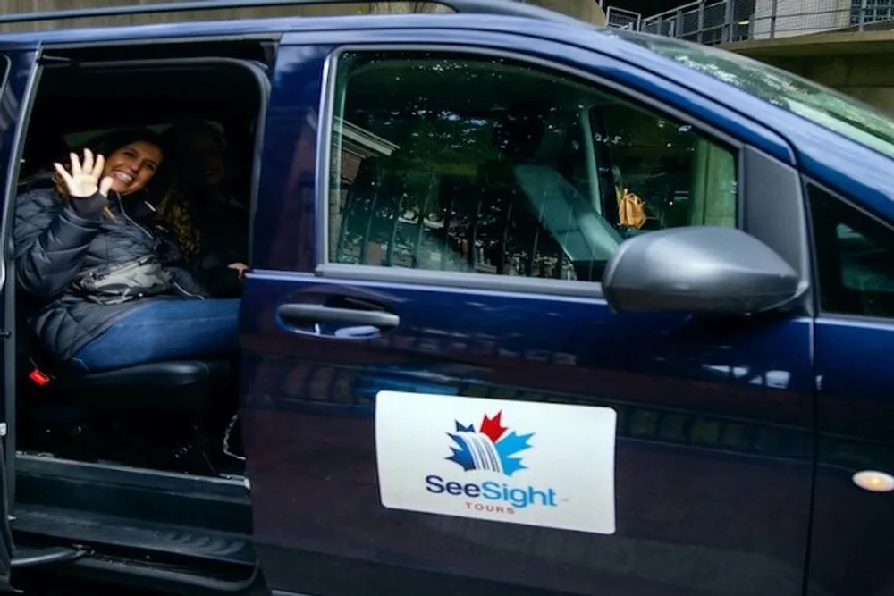 A smiling person is waving from inside a See Sight Tours branded vehicle