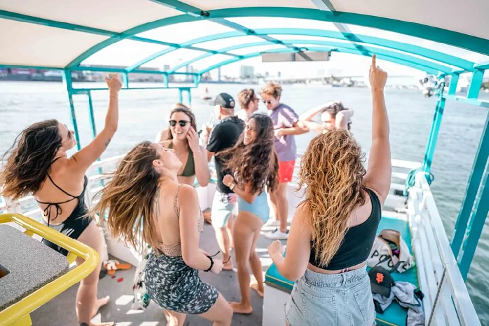 A group of people are joyfully dancing and socializing on a boat under a sunny sky
