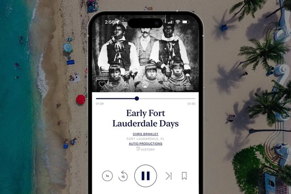 A smartphone displaying a historical audio story titled Early Fort Lauderdale Days is superimposed on an aerial view of a beach scene