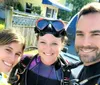 Three people in diving gear are posing for a selfie with bright smiles suggesting they are about to embark on a scuba diving adventure