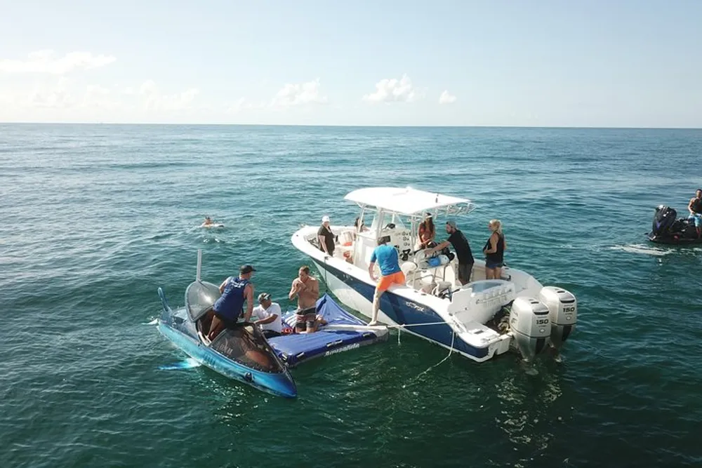 A group of people on and around two small boats is enjoying a sunny day on the calm sea with some individuals preparing for a dive