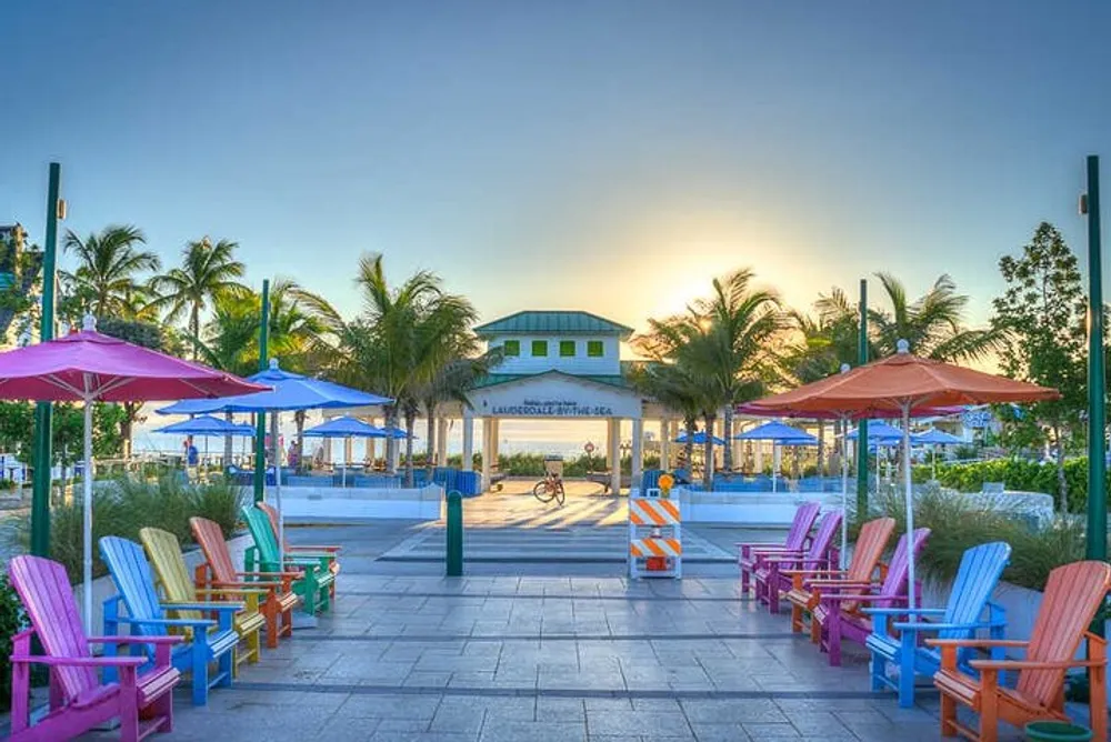 The image shows a vividly colorful seaside promenade with empty chairs and umbrellas during a serene sunset creating a peaceful inviting atmosphere