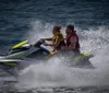 Two people are riding a yellow and purple jet ski over choppy waters creating a spray of water behind them
