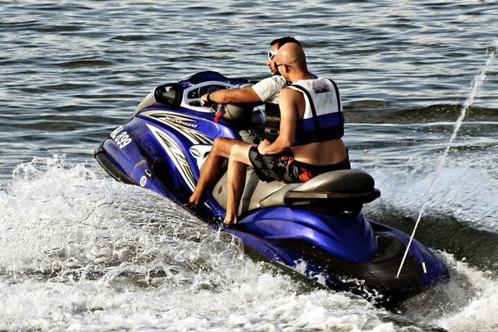 Two individuals are riding a blue and white personal watercraft creating splashes in the water