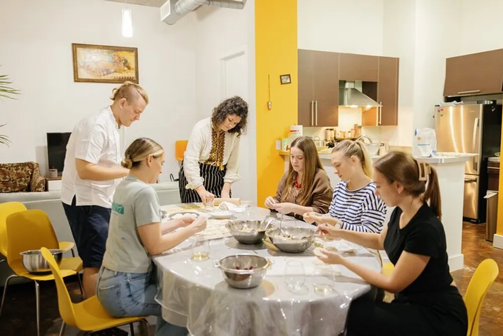 A group of people are preparing food together in a home kitchen setting