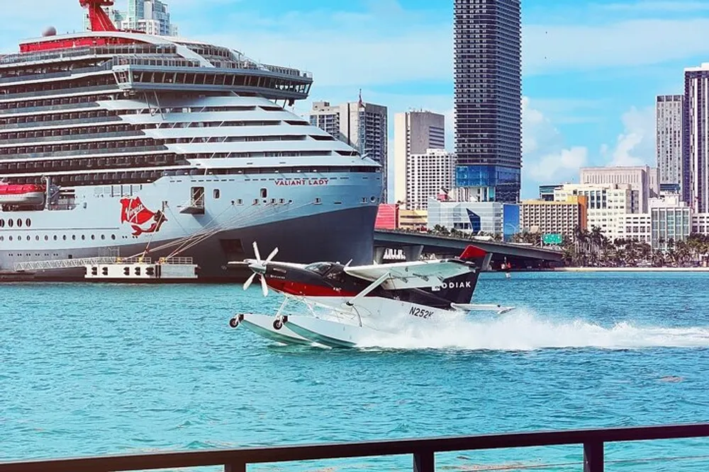 A seaplane is taking off in a bustling harbor with a large cruise ship docked in the background against a backdrop of a modern city skyline