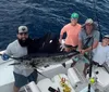 A person is holding a large fish with a big smile on their face standing on a boat with the ocean in the background