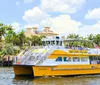 A water taxi with passengers is cruising along a river surrounded by lush tropical foliage