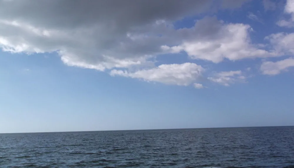 The image shows a serene view of the ocean under a partly cloudy sky