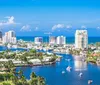 A person is looking towards a waterfront property lined with palm trees from a boat