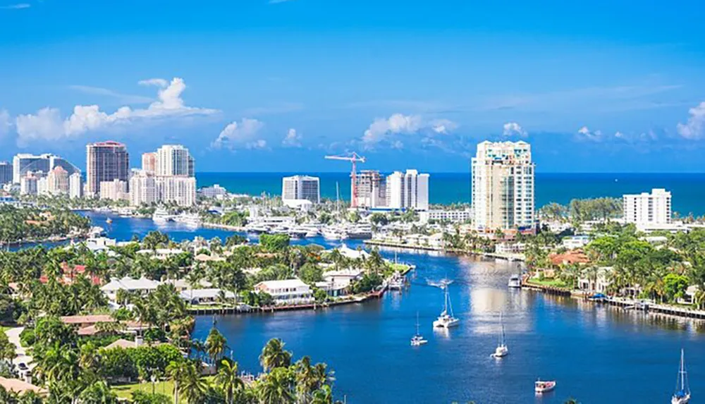 This image shows a panoramic view of a coastal city with high-rise buildings a marina with boats and clear blue skies