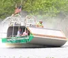 A group of people are enjoying a ride on an airboat gliding through a waterway likely in a swamp or wetlands area