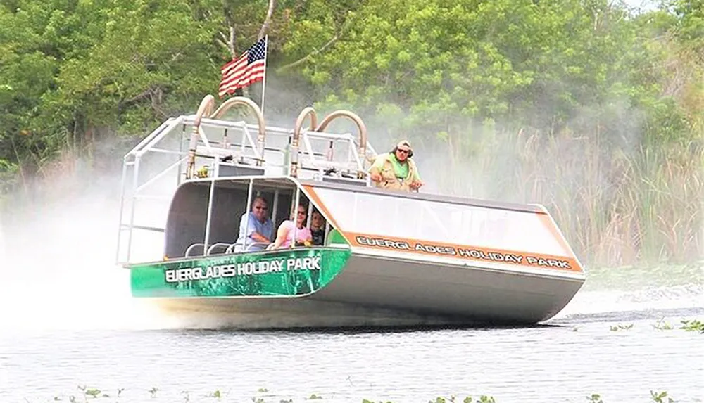 A group of people are enjoying a ride on an airboat gliding through a waterway likely in a swamp or wetlands area