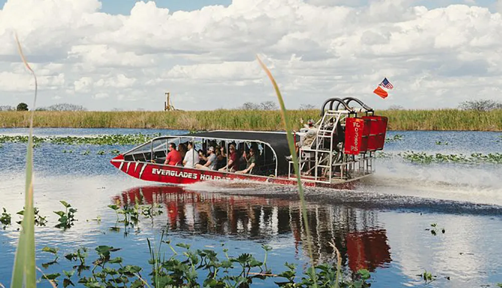 An airboat filled with passengers glides through the waters of the Everglades