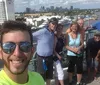 Three people are posing with two on Segways and one taking a selfie all smiling and having a good time near a fountain and yacht