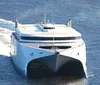 The image shows a modern high-speed catamaran ferry cutting through the water leaving a wake behind