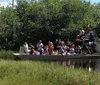 People are taking a tour on an airboat in a grassy wetland area