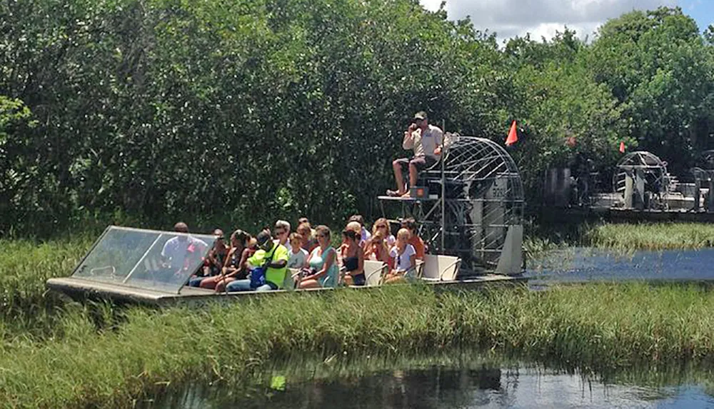 People are taking a tour on an airboat in a grassy wetland area