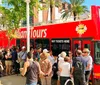 A group of people is waiting to board a red double-decker Miami Tours bus on a sunny day
