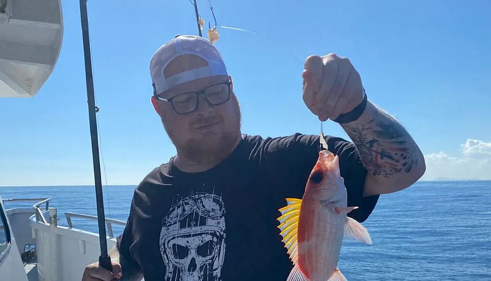 A person proudly displays a small fish caught on a sunny day aboard a boat at sea