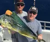 Two men are posing on a boat with a large fish they have caught