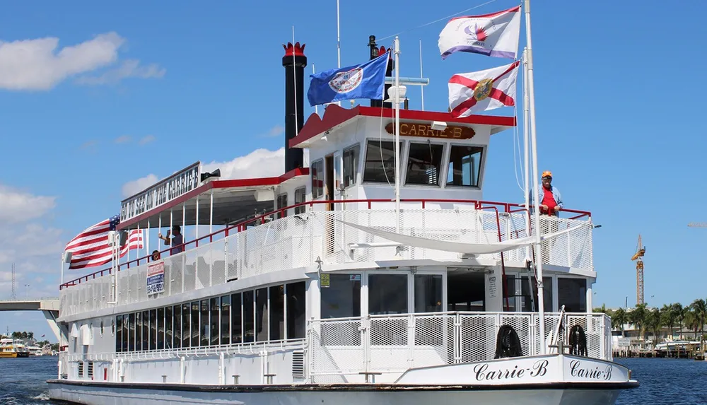 A paddlewheel boat named Carrie B adorned with flags sails under a blue sky